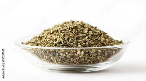 A close-up front view of a transparent bowl filled with dried oregano, with a white background emphasizing the rich detail of the seasoning.