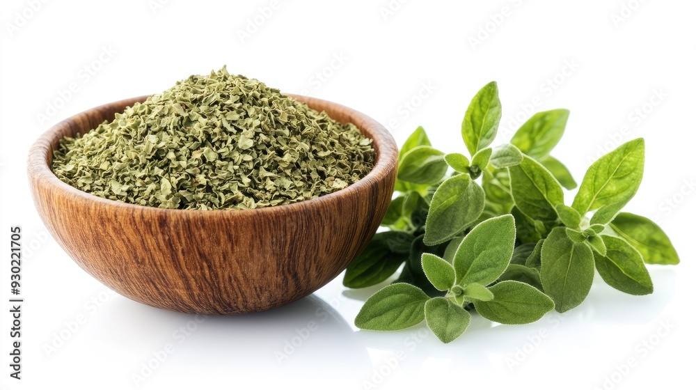 A front view of dried oregano flakes in a wooden bowl, with fresh oregano leaves laid out beside it, against a pure white background. A front view of dried oregano flakes in a wooden bowl, with fresh oregano leaves laid out beside it, against a pure white background.