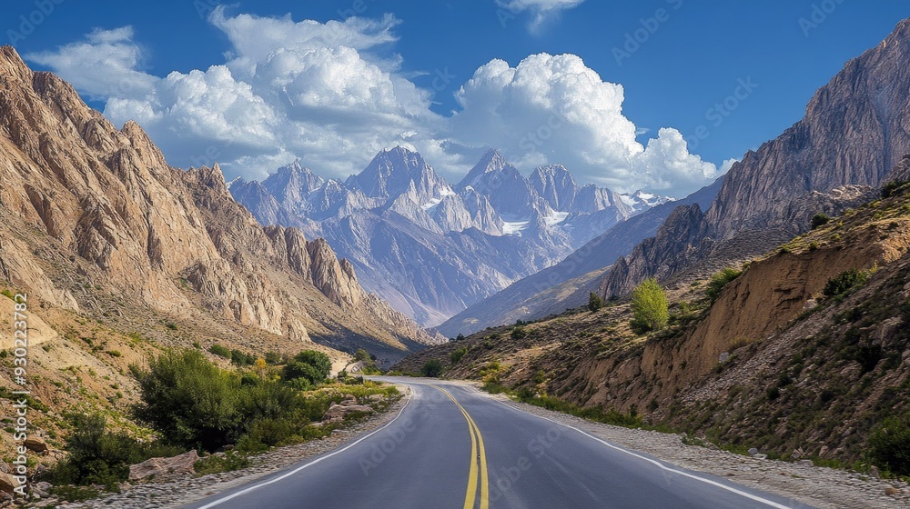 Fototapeta premium A scenic route through a mountainous area, with towering peaks and a clear blue sky in the background.