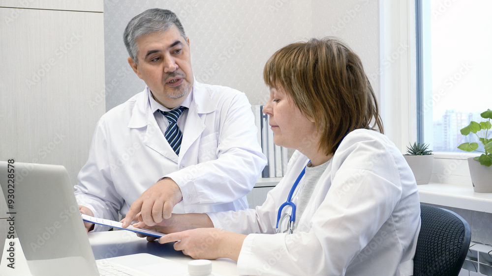 Supervisor checks the work of a female doctor Supervisor checks the work of a female doctor