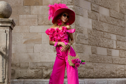 Spring summer fashion. High fashion model. Glamour, stylish elegant woman in pink jumpsuit and big hat. Female model in stylish look in the city. Outdoor shoot.