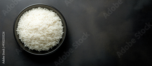 Bowl of white rice on a black background banner, top view.