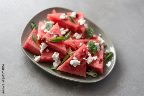 Fresh watermelon with feta cheese, baby spinach and lime juice on stone background. Healthy and aesthetic summer dessert, watermelon recipe. Top view photo