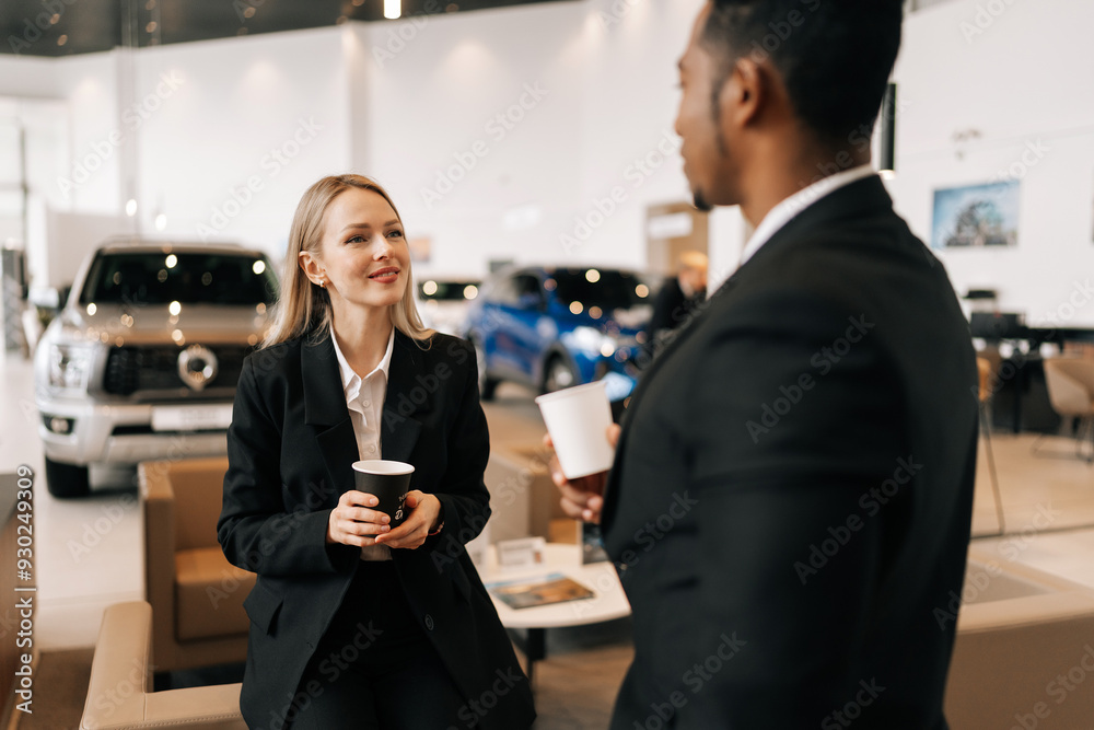 Rear view of relaxed multiethnic business people in formal outfit having break after meeting, talking during drinking coffee together in auto dealership. Concept for lifestyle of businesspeople. Rear view of relaxed multiethnic business people in formal outfit having break after meeting, talking during drinking coffee together in auto dealership. Concept for lifestyle of businesspeople.