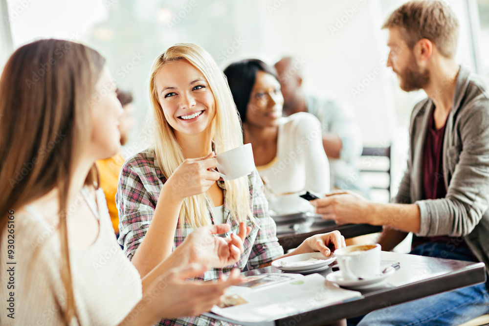 Diverse young friends drinking coffee in busy cafe Diverse young friends drinking coffee in busy cafe