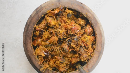 Overhead view of fresh palm nuts in a wood mortar, top view of palm nuts for making palm oil being pounded using a wooden mortar and pestle, process of making palm oil and nigerian banga soup photo