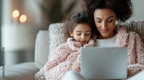 A woman and her daughter in fluffy sweaters, bonding over a tablet. Their shared moment of comfort and connection is highlighted in this cozy indoor setting.