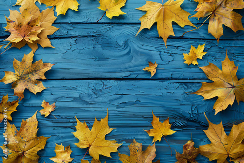 Autumn background with yellow maple leaves on a blue wooden table, in a top view. Space for text. Autumn concept. AI colorization of autumn leaves. Background for design and photo effects.