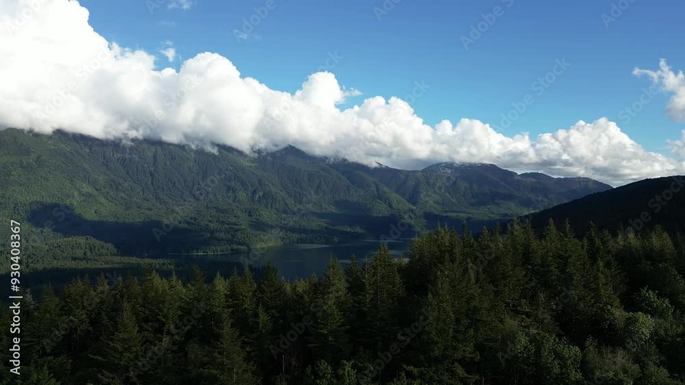 Beautiful mountain lake and forest on sunny day with large fluffy clouds stretching across the horizon. Serene, peaceful nature scene. British Columbia, Canada. Beautiful mountain lake and forest on sunny day with large fluffy clouds stretching across the horizon. Serene, peaceful nature scene. British Columbia, Canada.