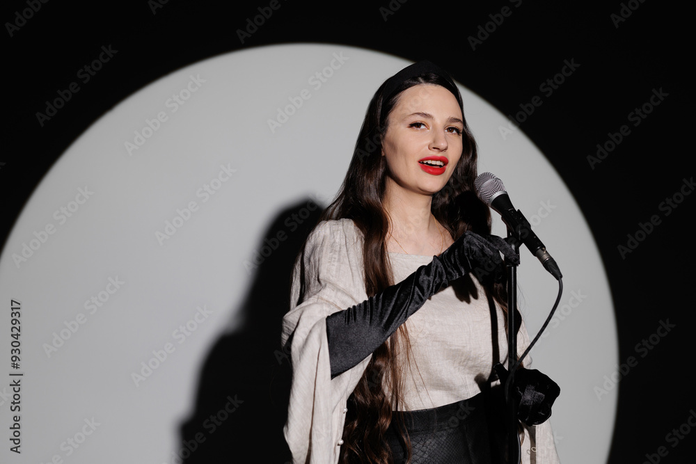 Singer with long hair and a microphone sings against the background of the spotlight. Singer with long hair and a microphone sings against the background of the spotlight.