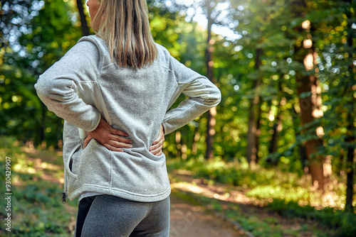 A Woman is Stretching in the Beautiful Nature, Relieving Her Back Pain While Enjoying the Fresh Air