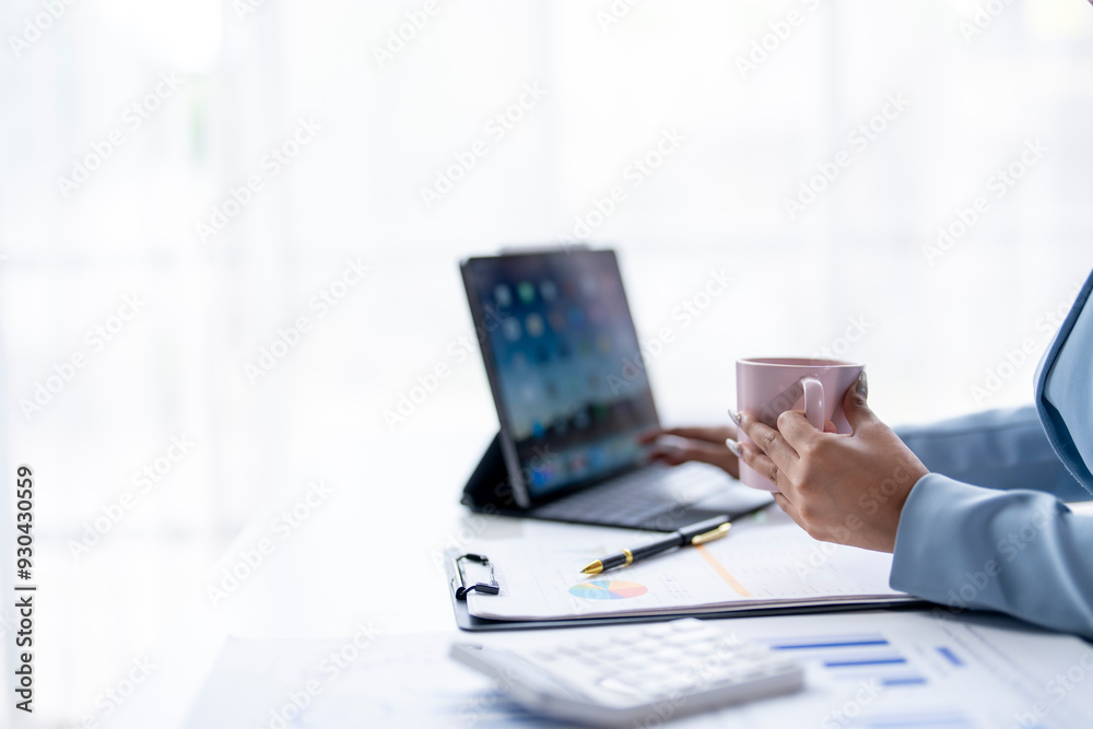 A woman is sitting at a desk with a laptop and a cup of coffee A woman is sitting at a desk with a laptop and a cup of coffee