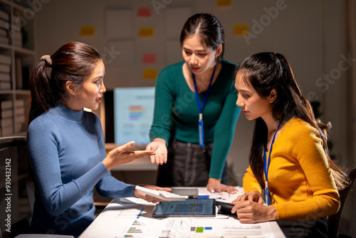 Three women are sitting at a table, discussing something