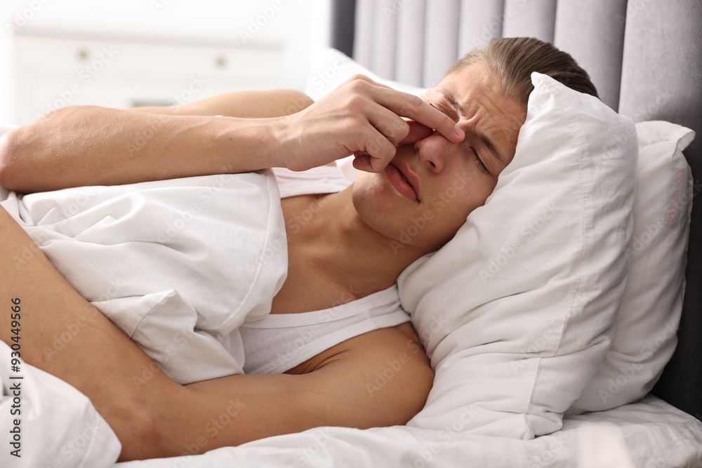 Young man suffering from sinusitis and lying in bed at home Young man suffering from sinusitis and lying in bed at home