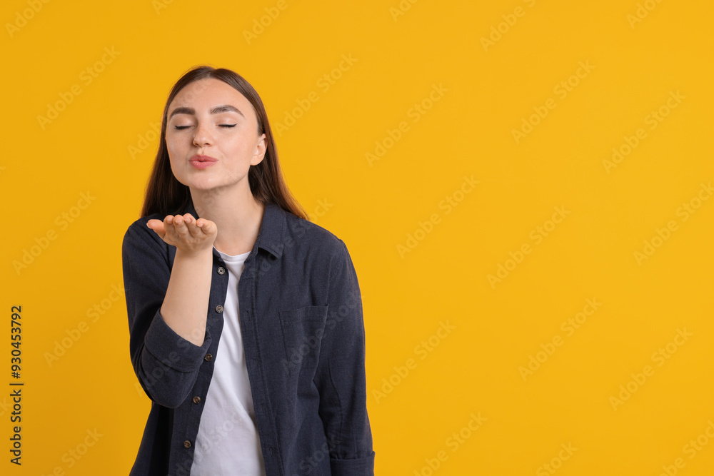 Beautiful woman blowing kiss on orange background, space for text Beautiful woman blowing kiss on orange background, space for text