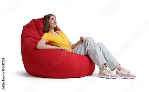 Beautiful young woman sitting on red bean bag chair against white background photo