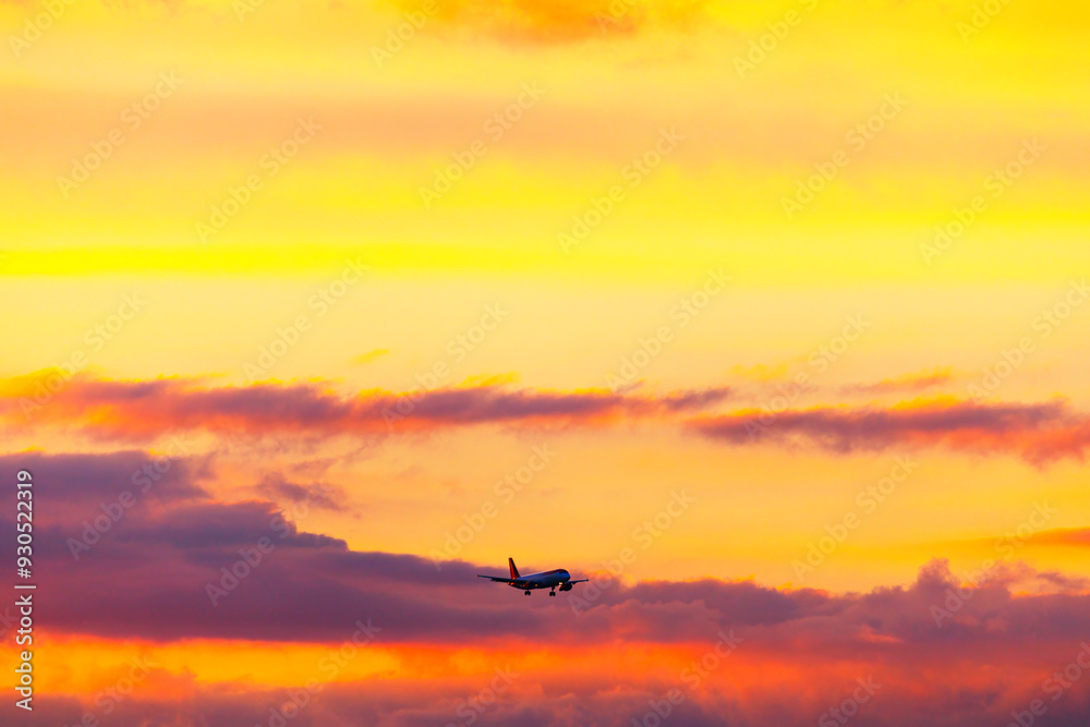 Plane is flying through a beautiful orange sky. Aircraft gliding gracefully across a bright sky, surrounded by fluffy colorful clouds Plane is flying through a beautiful orange sky. Aircraft gliding gracefully across a bright sky, surrounded by fluffy colorful clouds