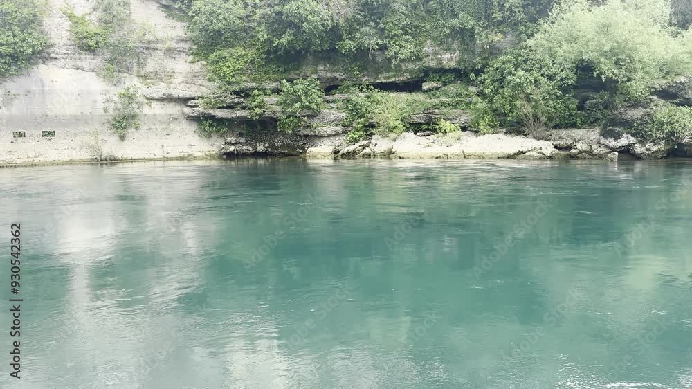 The green and cool river gurgles while the sky and the surrounding landscape are reflected on it The green and cool river gurgles while the sky and the surrounding landscape are reflected on it