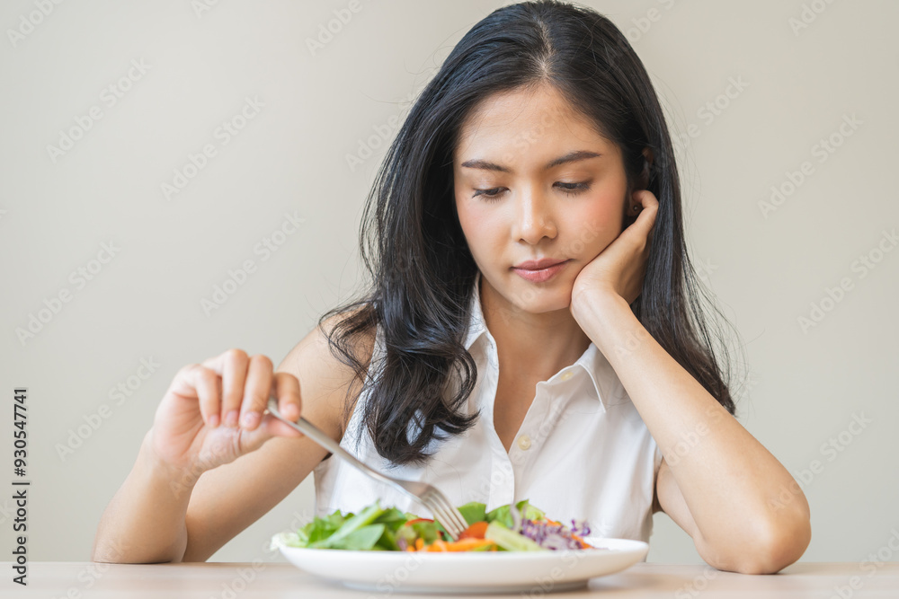 Diet in bored face, unhappy beautiful asian young woman, girl on dieting, holding fork at tomato on salad plate, dislike or tired with eat fresh vegetables. Nutrition of clean, healthy food good taste Diet in bored face, unhappy beautiful asian young woman, girl on dieting, holding fork at tomato on salad plate, dislike or tired with eat fresh vegetables. Nutrition of clean, healthy food good taste