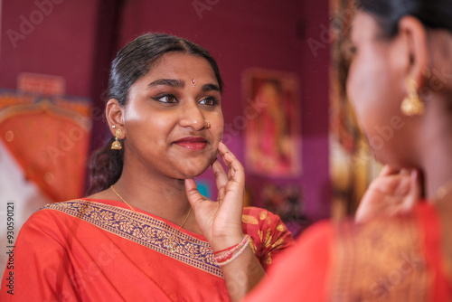 Woman of Hindu origin putting on makeup and preparing for the ceremony in front of the mirror. Concept: religion
