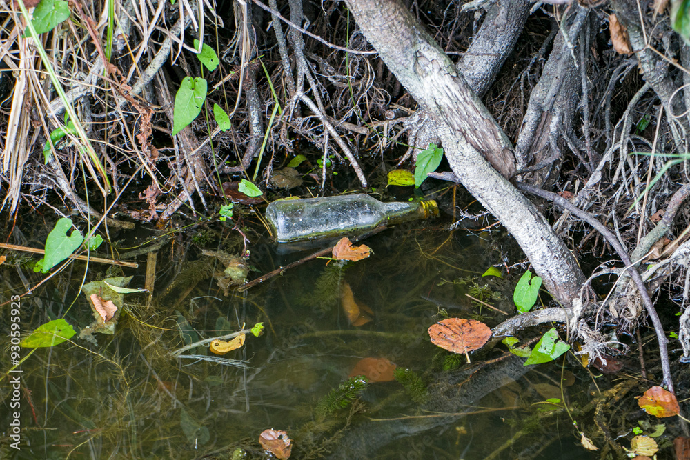 Empty glass bottle thrown into the river. Pollution of water bodies with garbage. Environmental problem. Empty glass bottle thrown into the river. Pollution of water bodies with garbage. Environmental problem.