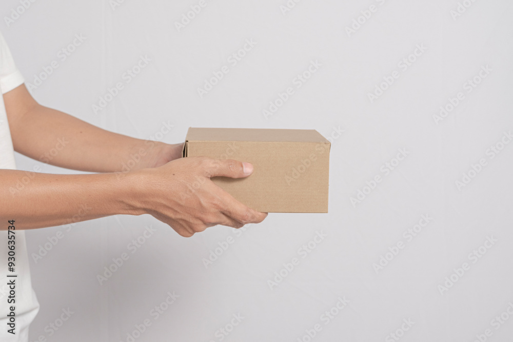 Obraz premium Image of a male courier's hand holding a package, box with a client's order. Delivery man distributes packages to customers on white background.