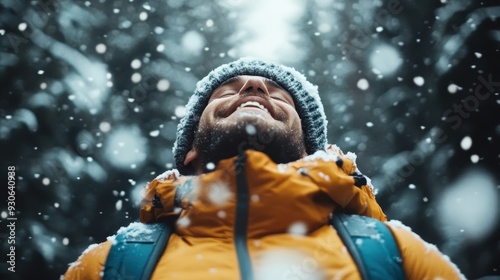 A person dressed in a yellow jacket with a knitted hat looks upward while standing amidst a forest during a snowfall, capturing the essence of wonder and tranquility in nature. photo