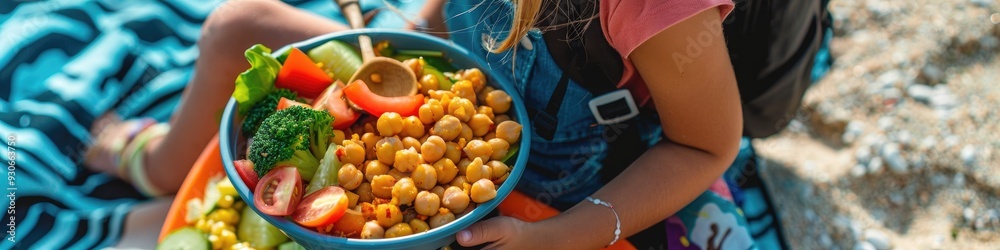 Child savoring plant-based meal featuring fresh vegetables and chickpeas during an outdoor picnic with a lunch box and backpack. Child savoring plant-based meal featuring fresh vegetables and chickpeas during an outdoor picnic with a lunch box and backpack.