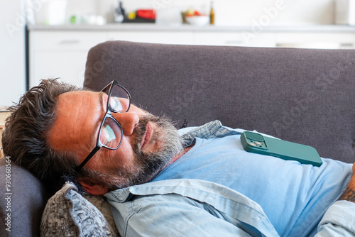 Obraz na plátně Exhausted man fell asleep on the comfortable sofa in the modern living room, without energy after a hard day at work