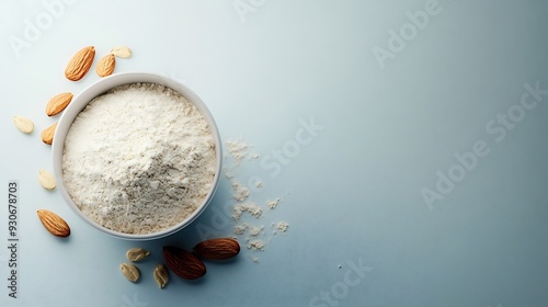 Almond flour in a white bowl with scattered almonds on a light blue background