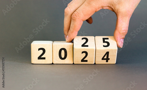 Business concept of 2025 new year symbol. Businessman turns wooden cube and changes number 2024 to 2025. Beautiful grey table grey background, copy space. Business 2025 happy new year concept.