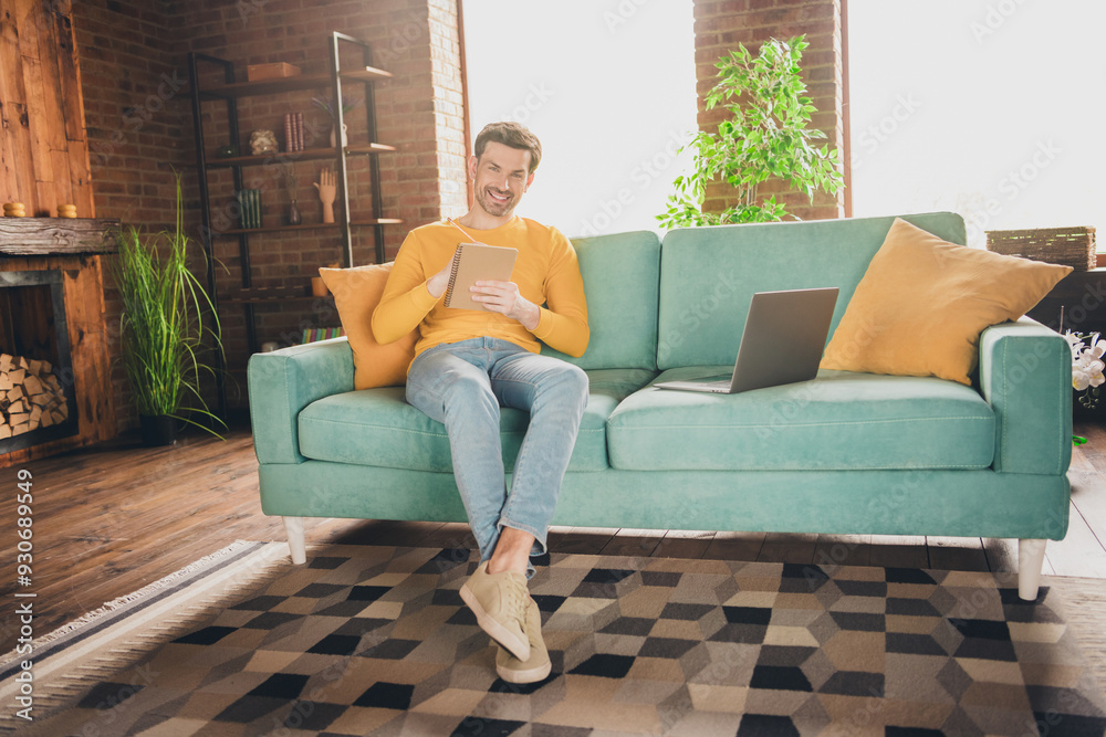 Full size photo of handsome mature man sit couch online study write notebook dressed yellow outfit cozy day light home interior living room Full size photo of handsome mature man sit couch online study write notebook dressed yellow outfit cozy day light home interior living room