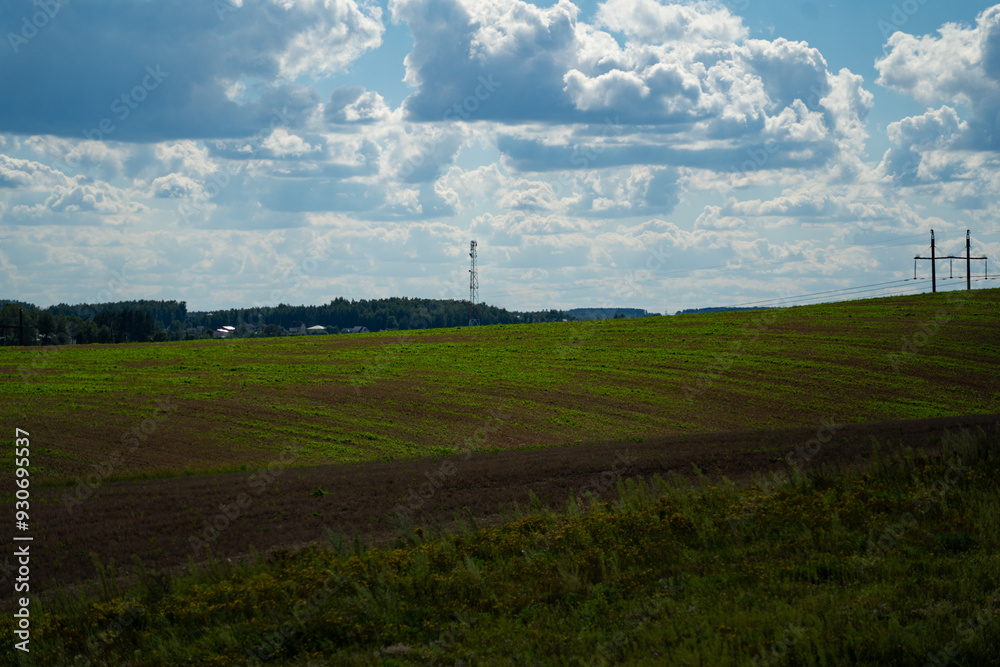 Thick clouds over green fields. The highway is far beyond the field Thick clouds over green fields. The highway is far beyond the field
