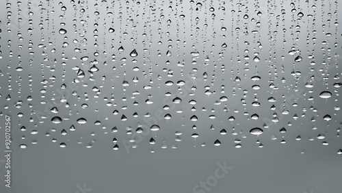 Full frame photo of water drops after rain. Raindrops running down a window pane on a dark, rainy day.