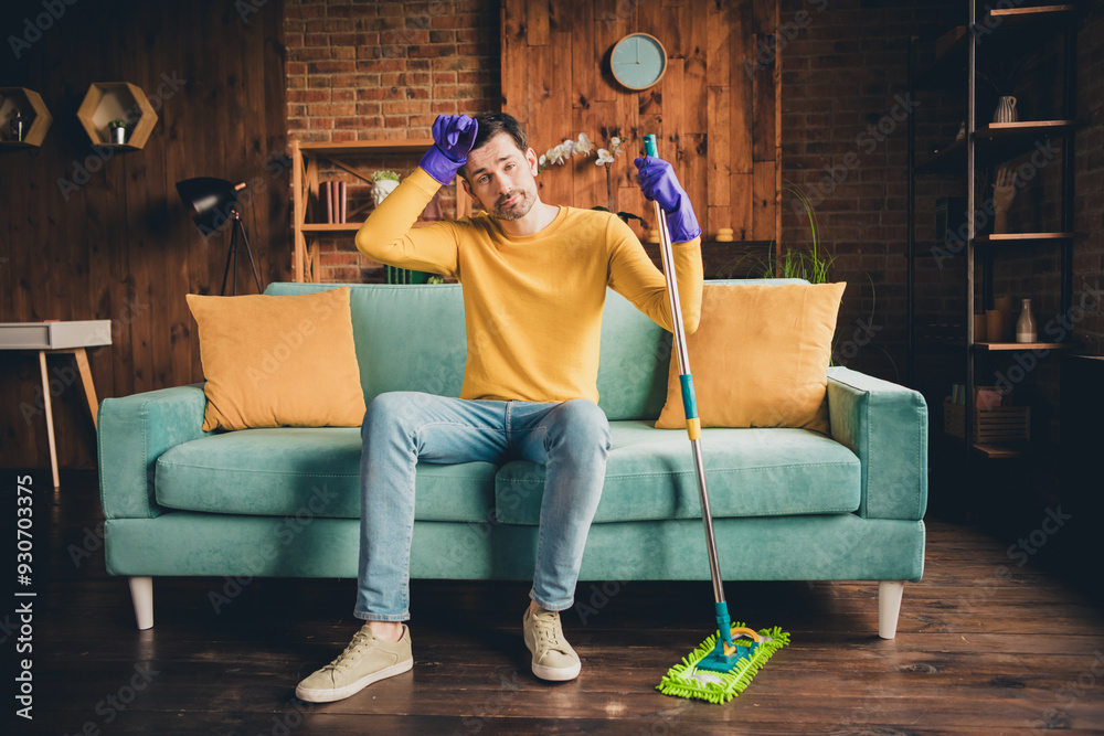 Obraz premium Full length photo of young guy mopping floor clean house sit couch tired dressed yellow garment spend pastime spacious house indoors room