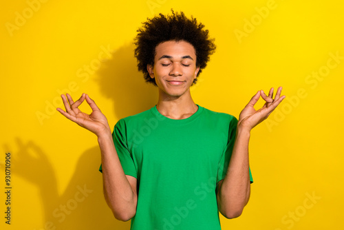 Photo of handsome good mood guy wear green t-shirt enjoying yoga emtpy space isolated yellow color background