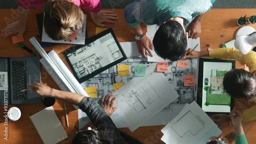 Top down view of manager writing project plan and sitting at meeting. Aerial view of business people planning and sharing idea about house construction at table with laptop and equipments. Symposium. © Summit Art Creations