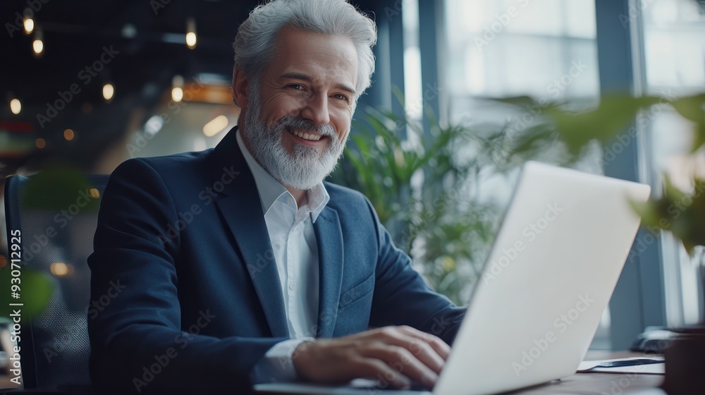 Smiling mature adult business man executive sitting at desk using laptop. Happy busy professional mid aged businessman ceo manager working on computer corporate technology in office