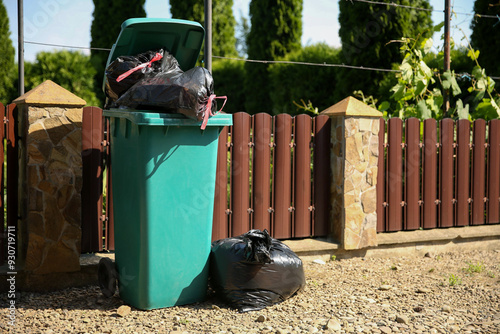 Trash bags full of garbage and bin outdoors photo