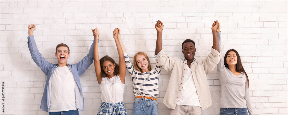 Φωτογραφία Joyful international group of teenagers raising joined hands up together over wh