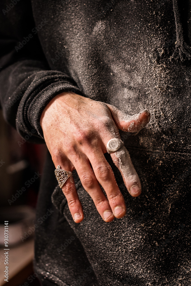Dust-covered fingers of a skilled woodworker, accentuated by decorative rings, evoke the rugged beauty of manual craftsmanship. Vertical photo