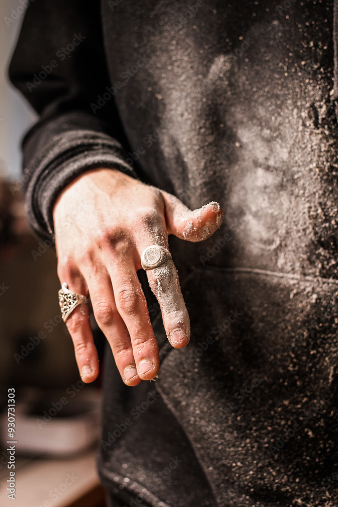 Dust-covered fingers of a skilled woodworker, accentuated by decorative rings, evoke the rugged beauty of manual craftsmanship. Vertical photo