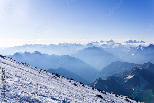 view from highland snowy slope to misty mountains in the rays of dawn photo