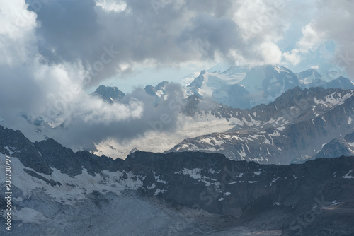 beautiful mountainous landscape, peaks and glaciers among clouds photo