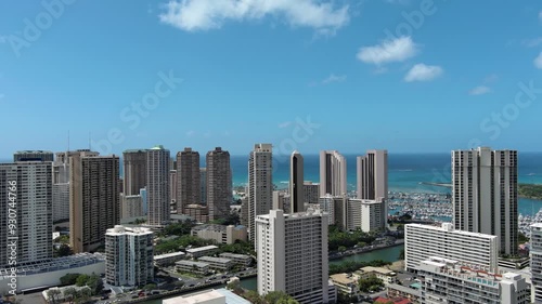 panning aerial footage of skyscrapers, hotels and condos, the pacific ocean, boats and yachts, cars on the street, blue sky and clouds in Honolulu Hawaii USA photo