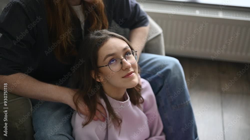 A young guy gives a shoulder massage to his girlfriend at home. Slow motion, depiction of love and care