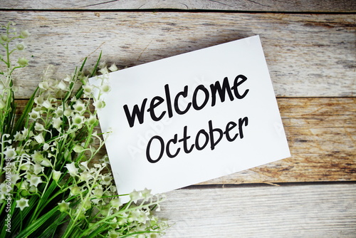 Welcome October text on paper card with flowers frame top view on wooden background