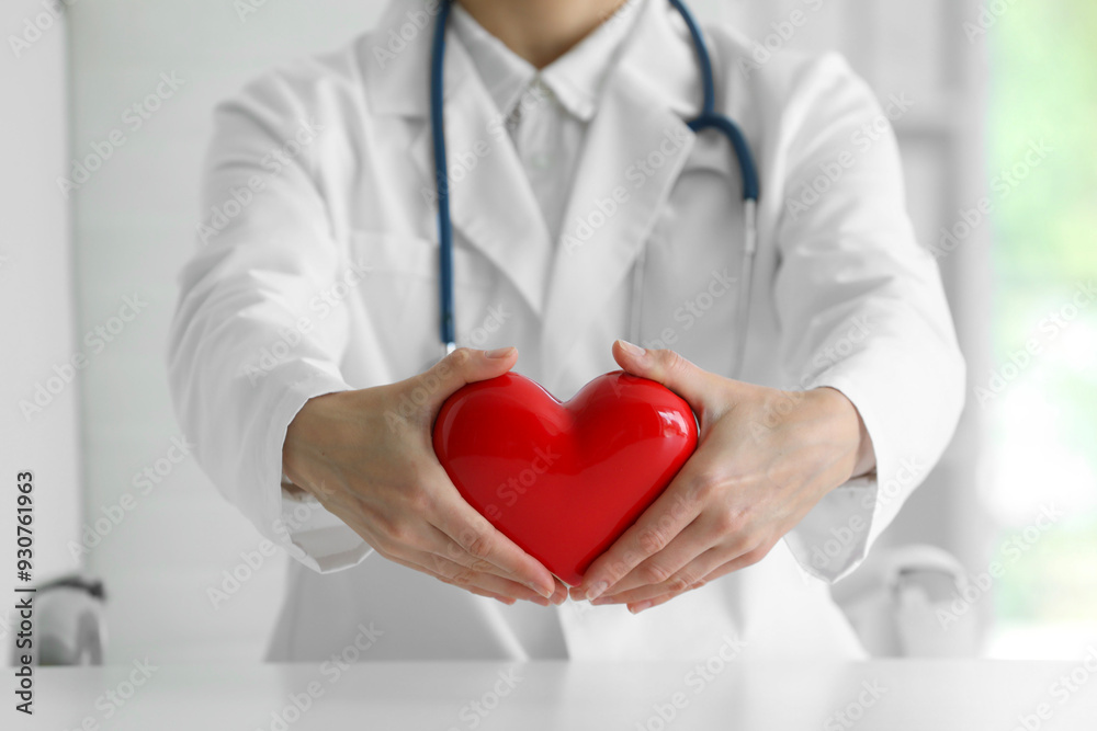 Doctor with red heart at table in clinic, closeup Doctor with red heart at table in clinic, closeup