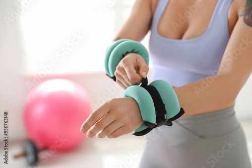 Fototapeta Naklejka Na Ścianę i Meble -  Woman putting ankle weight on her arm indoors, closeup