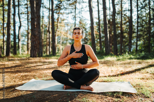 Young caucasian woman doing yoga stretching and meditating in forest